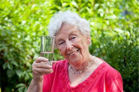 Smiling old woman holding glass of water Stock Photo - Premium Royalty-Free, Code: 628-07072575