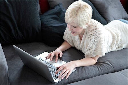 simsearch:628-07072884,k - Smiling young woman using laptop on couch Stock Photo - Premium Royalty-Free, Code: 628-07072694