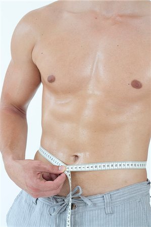 simsearch:689-03733468,k - Young man measuring his waist Stock Photo - Premium Royalty-Free, Code: 628-07072973