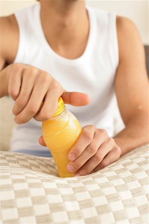 pictures man opening bottle - Young man opening a bottle of juice Stock Photo - Premium Royalty-Free, Code: 628-00918615