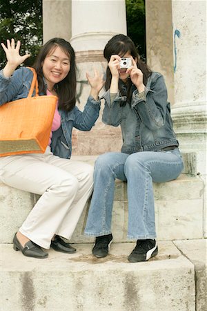 Two Asian women sitting on the stairs of a monument, one of them with a camera in her hand Stock Photo - Premium Royalty-Free, Code: 628-00919109