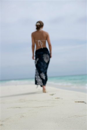 Young girl walking along the beach, footprints in the sand, rear view Stock Photo - Premium Royalty-Free, Code: 628-00919227