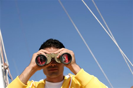 Man looking trough binoculars Stock Photo - Premium Royalty-Free, Code: 628-00919886