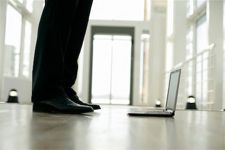 Businessman standing near a laptop Stock Photo - Premium Royalty-Free, Code: 628-00920537