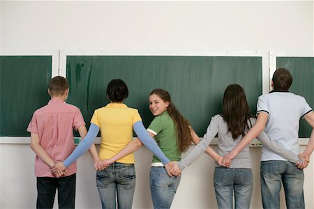 A group of teenagers standing in front of blackboard and holding hands Stock Photo - Premium Royalty-Free, Code: 628-00920608