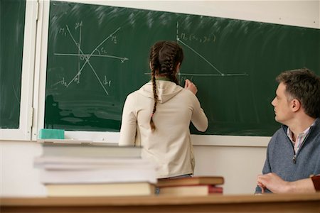 Teenage girl writing on blackboard, teacher is watching her Foto de stock - Sin royalties Premium, Código: 628-00920653