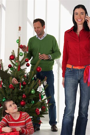 father christmas family portrait - Family in Christmassy room, mother phoning with a mobile phone, father decorating the Christmas tree Stock Photo - Premium Royalty-Free, Code: 628-01278549