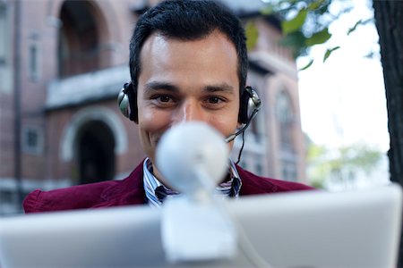 Man with headset using a laptop with webcam Stock Photo - Premium Royalty-Free, Code: 628-01278595