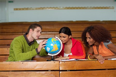 Three young people looking at a miniature-globe, selective focus Stock Photo - Premium Royalty-Free, Code: 628-01279216