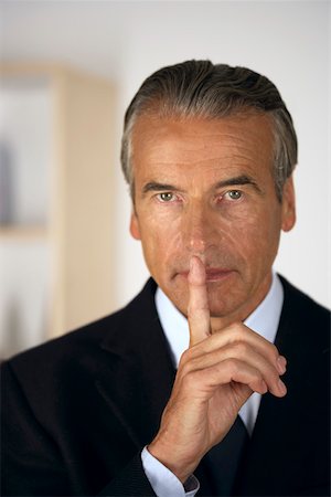 shhh - Senior businessman holding a finger in front of his mouth Stock Photo - Premium Royalty-Free, Code: 628-01279620