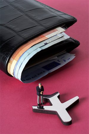 symbol for intelligence - Businessman figurine on a model plane, wallet with banknotes in background Stock Photo - Premium Royalty-Free, Code: 628-01279706