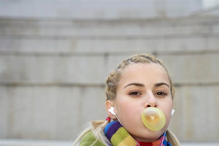 Young woman listening to music about earphones chewing gum Stock Photo - Premium Royalty-Free, Code: 628-01495316