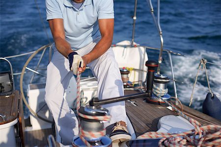 Man on a sailboat pulling a rope Stock Photo - Premium Royalty-Free, Code: 628-01495445