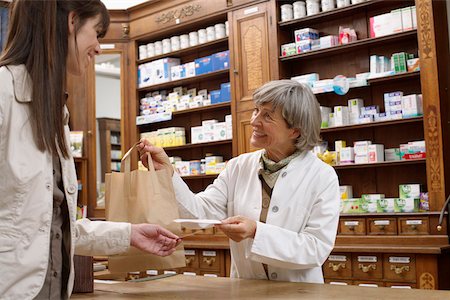 Female pharmacist handing over drugs and prescription to female customer Stock Photo - Premium Royalty-Free, Code: 628-01586644