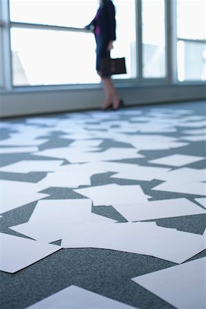 Businesswoman standing in an empty office, sheets of paper on floor Stock Photo - Premium Royalty-Free, Code: 628-01639088