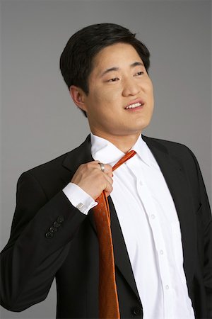 Asian businessman pulling his tie Stock Photo - Premium Royalty-Free, Code: 628-01712133