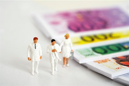 Figurines of doctors beside banknotes Stock Photo - Premium Royalty-Free, Code: 628-01712324