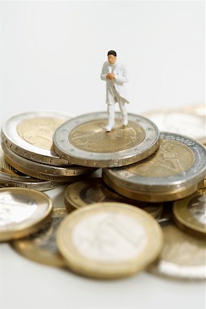 Figurine of a doctor on a heap of coins Stock Photo - Premium Royalty-Free, Code: 628-01712347