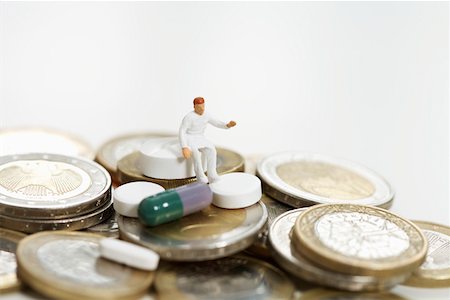 Figurine of a doctor and pills on heap of coins Stock Photo - Premium Royalty-Free, Code: 628-01712342