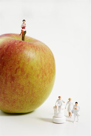 Female figurine on an apple, figurines of doctors beside Stock Photo - Premium Royalty-Free, Code: 628-01712366