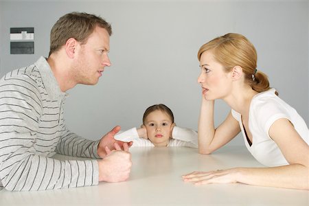 Couple arguing at table, girl in background covering ears with hands Stock Photo - Premium Royalty-Free, Code: 628-02197937