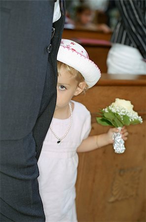 shy baby - Little Girl in a white Dress with a Bunch of Flowers in her Hand hiding behind a Grown-Up - Bashfulness - Church - Celebration - Baptism - Christianity Stock Photo - Premium Royalty-Free, Code: 628-02615784