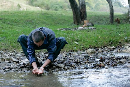 rivulet - Brunette man is washing his hands at the shore of a rivulet Stock Photo - Premium Royalty-Free, Code: 628-02954365