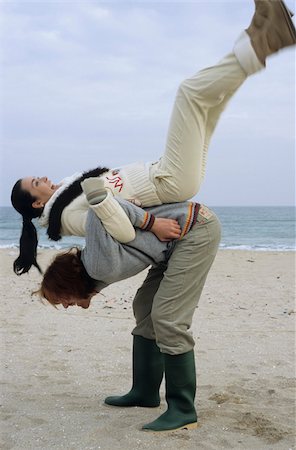 Longhaired Man pulling his Girlfriend onto his Back - Fun - Physicalness - Relationship - Beach Stock Photo - Premium Royalty-Free, Code: 628-02954602
