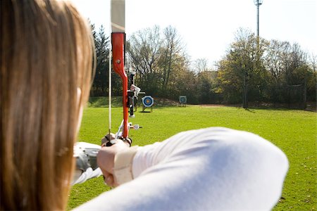 Female archer aiming arrow at target board, Munich, Bavaria, Germany Foto de stock - Sin royalties Premium, Código: 628-02953512