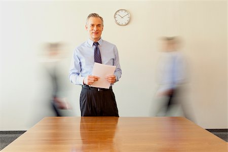 Businessman holding papers with people in background passing by, Munich, Bavaria, Germany Stock Photo - Premium Royalty-Free, Code: 628-02953648