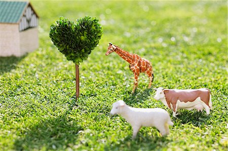 Cow, Giraffe, Sheep And Heart Shape Tree With Hut On Grassy Field Stock Photo - Premium Royalty-Free, Code: 622-06163865