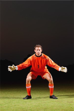 Goalkeeper in orange uniform standing in soccer field Stock Photo - Premium Royalty-Free, Code: 622-07736084