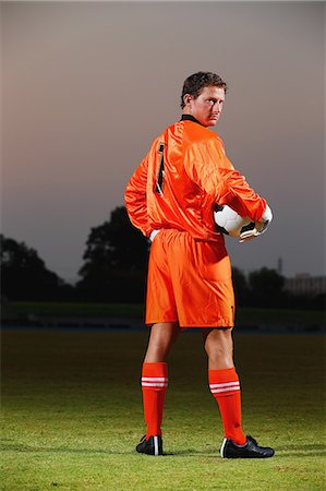 Goalkeeper in orange uniform standing in soccer field Stock Photo - Premium Royalty-Free, Code: 622-07736086