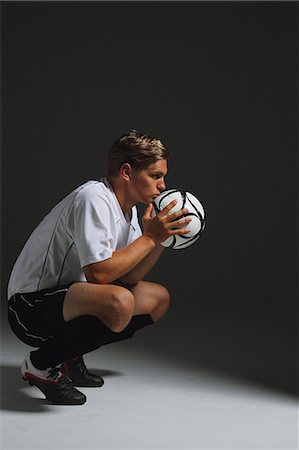 soccer player holding ball - Soccer Player Crouching With Ball Stock Photo - Premium Royalty-Free, Code: 622-07736100
