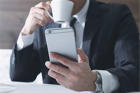 picture of person holding cup - Japanese businessman working with large display smartphone Stock Photo - Premium Royalty-Free, Code: 622-08122877