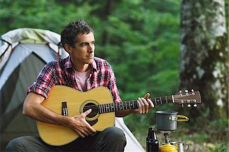 Caucasian man playing guitar at a camp site Stock Photo - Premium Royalty-Free, Code: 622-08519657