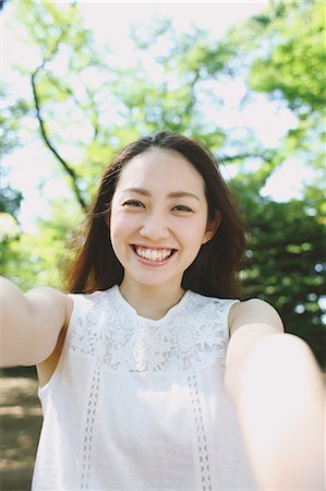 Young Japanese woman surrounded by green in a city park Stock Photo - Premium Royalty-Free, Code: 622-08765675