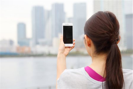 Attractive Japanese woman taking pictures by a river downtown Tokyo, Japan Stock Photo - Premium Royalty-Free, Code: 622-08839867