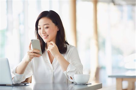 Japanese woman with smartphone in a stylish cafe Stock Photo - Premium Royalty-Free, Code: 622-09014306