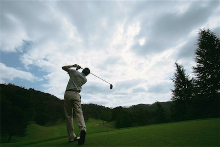 A man swings a golf club against a dramatic sky Stock Photo - Premium Royalty-Free, Code: 622-00806967