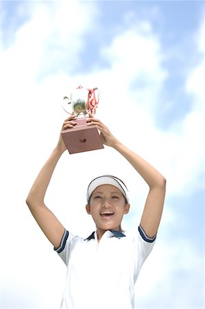 Low angle view of a woman raising a golf trophy in excitement Stock Photo - Premium Royalty-Free, Code: 622-00807201