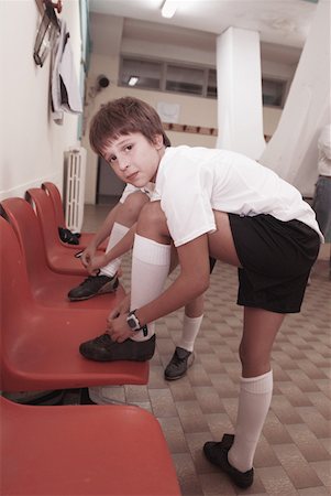 football player in locker room - Boy tying his cleats Stock Photo - Premium Royalty-Free, Code: 622-01283832