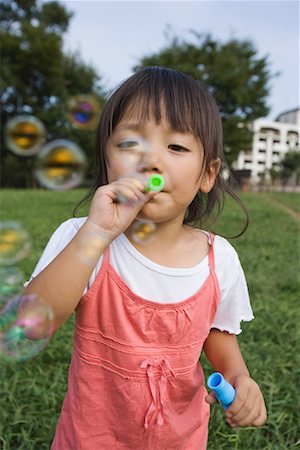 Girl blowing soap bubbles in park Stock Photo - Premium Royalty-Free, Code: 622-02354151