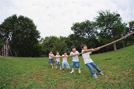 forced smile - Children playing Tug-Of-War in park Stock Photo - Premium Royalty-Free, Code: 622-02354172