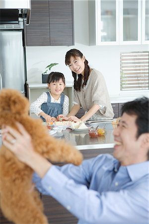 spare parts - Father holding dog with family in background Stock Photo - Premium Royalty-Free, Code: 622-02759183