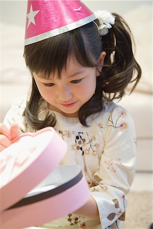 Asian girl opening her birthday present Stock Photo - Premium Royalty-Free, Code: 622-02759215