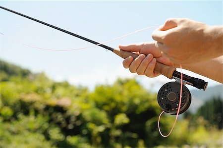 Hands holding fishing rod and reel Stock Photo - Premium Royalty-Free, Code: 622-02913475