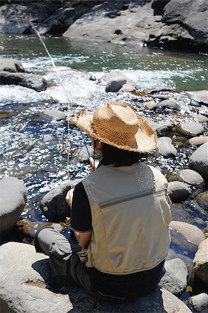Man with straw hat sitting on stone and fishing Stock Photo - Premium Royalty-Free, Code: 622-02913477