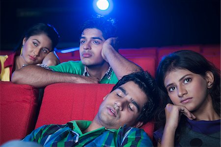 Youngsters feeling bored while watching movie in a cinema hall Stock Photo - Premium Royalty-Free, Code: 630-06724518