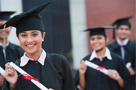 Portrait of graduate students holding diplomas and smiling in university campus Stock Photo - Premium Royalty-Free, Code: 630-06724608